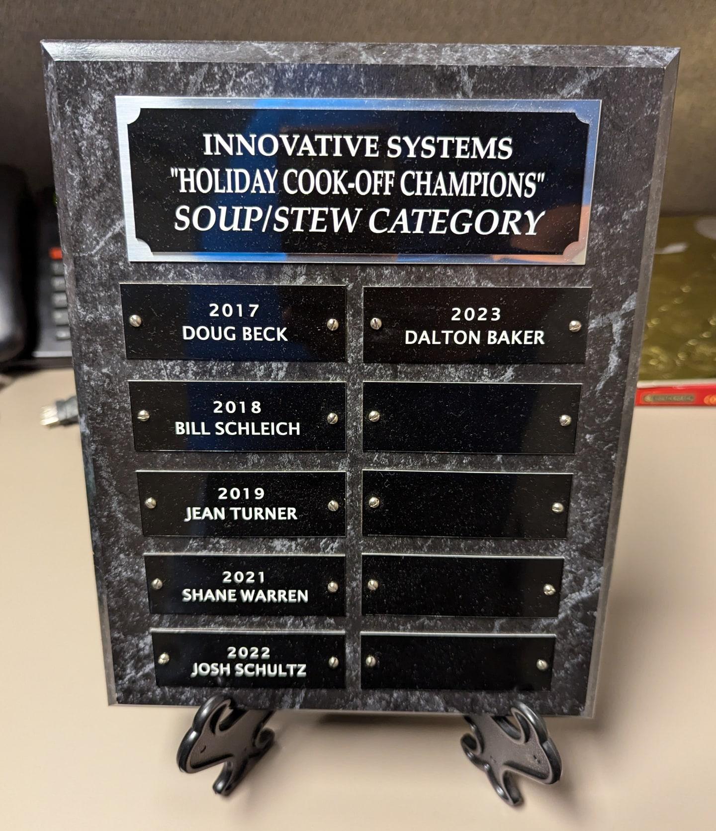 The Innovative Systems Holiday Cook-Off Champions plaque for the soup/stew category, with Dalton Baker on the 2023 plate